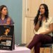 Mujer hablando en evento cultural con micrófono en mano.