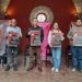 Cartel de evento teatral en un espacio histórico con cuatro personas sosteniendo carteles.