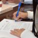 Persona firmando documento en mesa de trabajo.