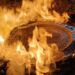 Manhole cover burning amidst flames, symbolizing cultural resilience and social issues in Michoacán.