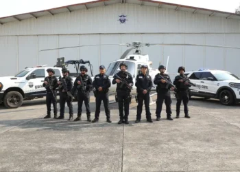 Personal de Guardia Civil en Michoacán posando con vehículos y helicóptero en un hangar.