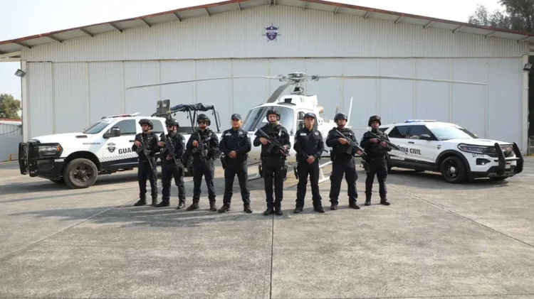 Personal de Guardia Civil en Michoacán posando con vehículos y helicóptero en un hangar.