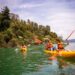 Personas remando en kayak en el lago Zirahuén, rodeados de naturaleza y montañas, disfrutando del turismo deportivo en Michoa.