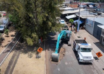 Amplia excavadora y camión en obra de boulevard en Ario, Michoacán, con señalización y trabajadores en sitio.