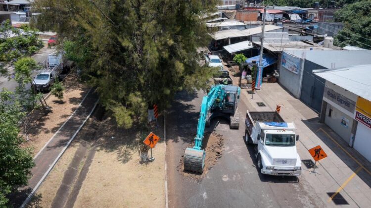 Amplia excavadora y camión en obra de boulevard en Ario, Michoacán, con señalización y trabajadores en sitio.