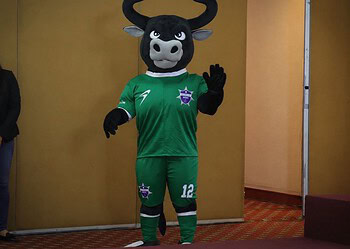 Mascota de equipo de fútbol con disfraz de toro en evento internacional de policías y bomberos en Michoacán.