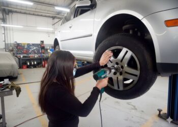 Mujer realiza mantenimiento a un vehículo en taller de capacitación automotriz.