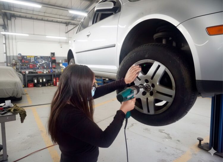 Mujer realiza mantenimiento a un vehículo en taller de capacitación automotriz.