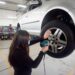 Mujer realiza mantenimiento a un vehículo en taller de capacitación automotriz.
