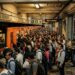 Multitud de pasajeros esperando en la plataforma del metro en una estación concurrida.