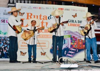 Escenario con niños tocando guitarras en evento cultural de lectura.