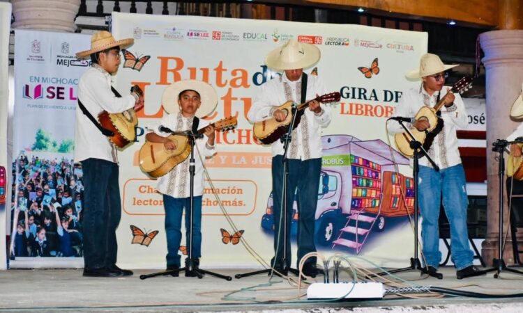 Escenario con niños tocando guitarras en evento cultural de lectura.