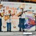 Escenario con niños tocando guitarras en evento cultural de lectura.