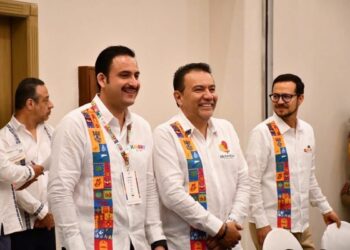 Líderes en evento de turismo con banderas y sonrisas en reunión oficial.