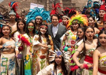 Grupo de personas con trajes tradicionales y plumas en Teotihuacán, celebrando el encendido del Fuego Nuevo rumbo a Juegos Ce.