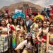 Grupo de personas con trajes tradicionales y plumas en Teotihuacán, celebrando el encendido del Fuego Nuevo rumbo a Juegos Ce.