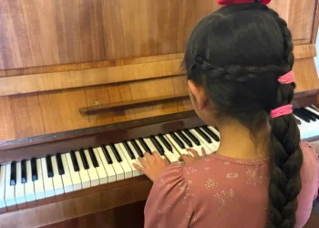 Niña tocando el piano en un evento cultural en Michoacán, promoviendo la música y las bandas comunitarias en la región.