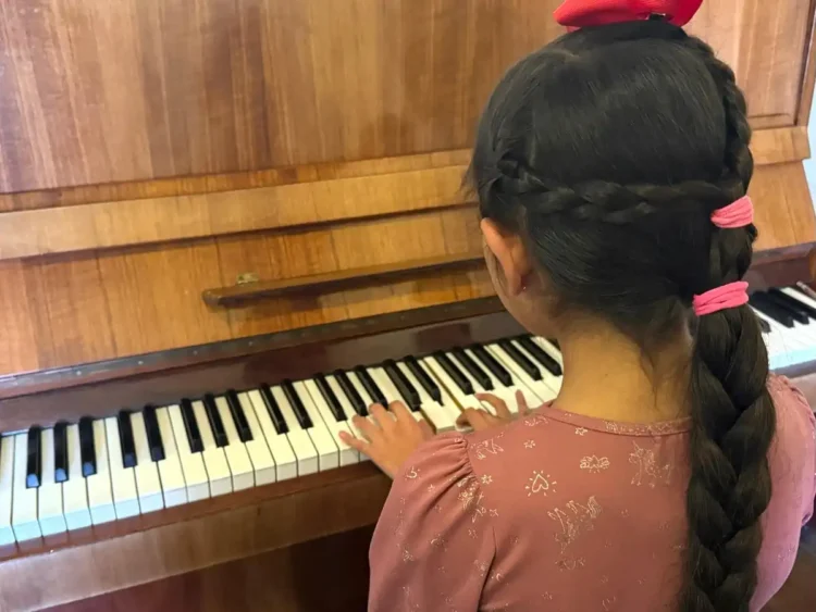 Niña tocando el piano en un evento cultural en Michoacán, promoviendo la música y las bandas comunitarias en la región.