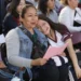 Dos mujeres sonrientes en un evento escolar, compartiendo un momento de alegría y camaradería entre estudiantes y docentes en.