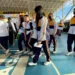 Estudiantes con uniformes deportivos en un espacio cerrado, participando en actividades relacionadas con el baloncesto.