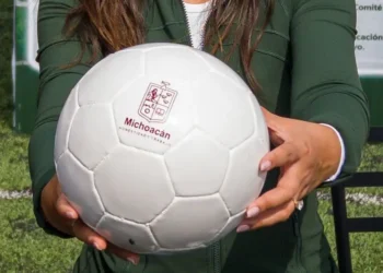 Persona sosteniendo un balón de fútbol con logotipo de Michoacán.