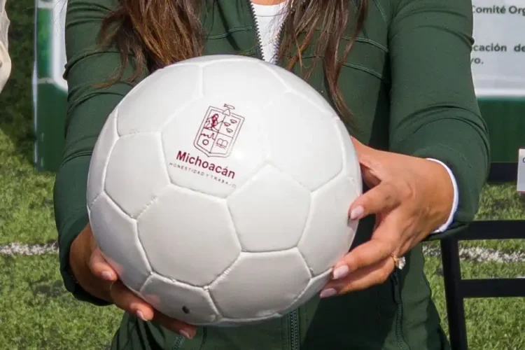 Persona sosteniendo un balón de fútbol con logotipo de Michoacán.