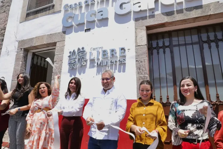 Grupo de mujeres y un hombre en la inauguración del Centro Libre de Mujeres en Michoacán, con sonrisas y documentos en mano.