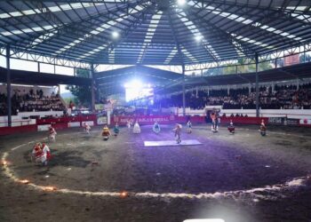 Policías y bomberos participan en un evento en un circo con público en las gradas.