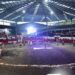 Policías y bomberos participan en un evento en un circo con público en las gradas.
