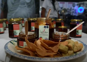 Mermeladas de mango en frascos pequeños acompañadas de galletas y papeles de seda en una bandeja.