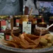 Mermeladas de mango en frascos pequeños acompañadas de galletas y papeles de seda en una bandeja.