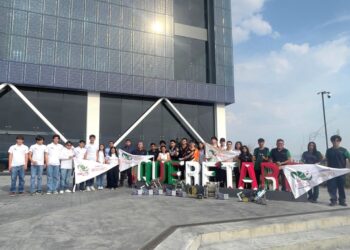Estudiantes y docentes muestran su talento en robótica frente a un edificio moderno.
