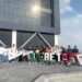 Estudiantes y docentes muestran su talento en robótica frente a un edificio moderno.