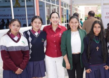 Estudiantes y docente posan en la entrada de una escuela, promoviendo la educación y oportunidades para todos en Michoacán.