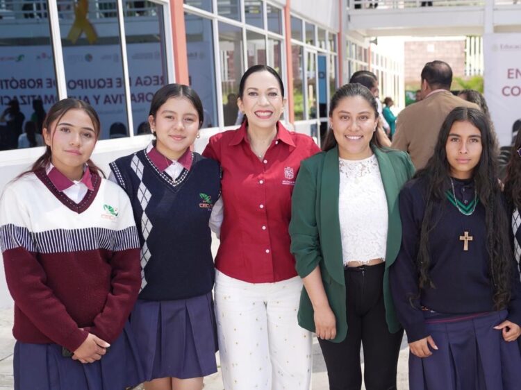 Estudiantes y docente posan en la entrada de una escuela, promoviendo la educación y oportunidades para todos en Michoacán.