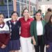 Estudiantes y docente posan en la entrada de una escuela, promoviendo la educación y oportunidades para todos en Michoacán.