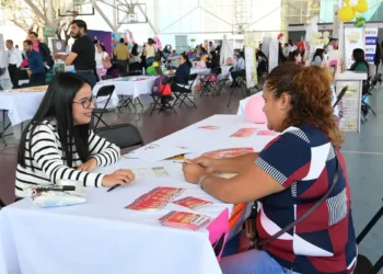 Mujer en feria de empleo en Michoacán conversando con una representante.