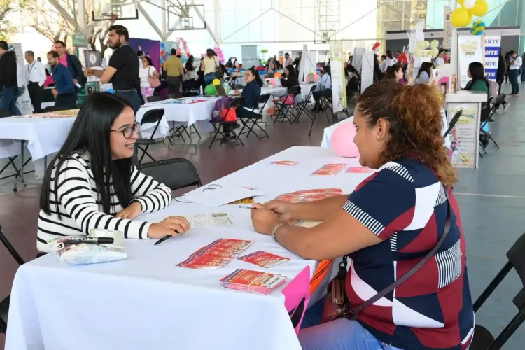 Mujer en feria de empleo en Michoacán conversando con una representante.