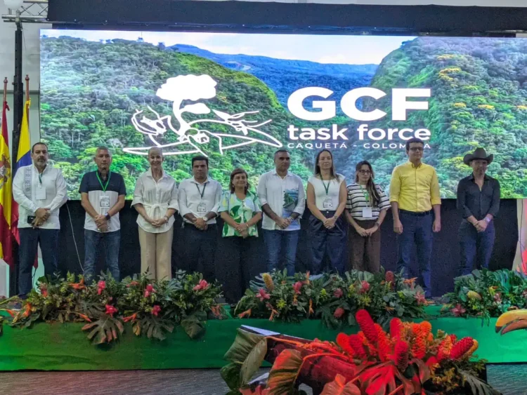 Grupo de personas en una conferencia con fondo digital de naturaleza y logo de GCF.