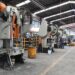 Maquinarias industriales en una planta de producción con maquinaria pesada y operarios trabajando en un ambiente industrial.