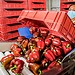 Mujer con mascarilla inspecciona pimientos morrones rojos en un almacén de producción agrícola.