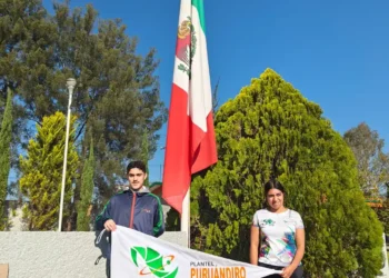 Jóvenes sosteniendo una bandera mexicana y un cartel en un parque con árboles y cielo despejado.
