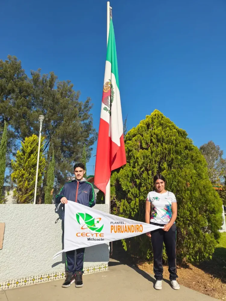 Jóvenes sosteniendo una bandera mexicana y un cartel en un parque con árboles y cielo despejado.