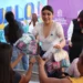 Mujer entrega paquetes a niños en evento cultural en Michoacán.