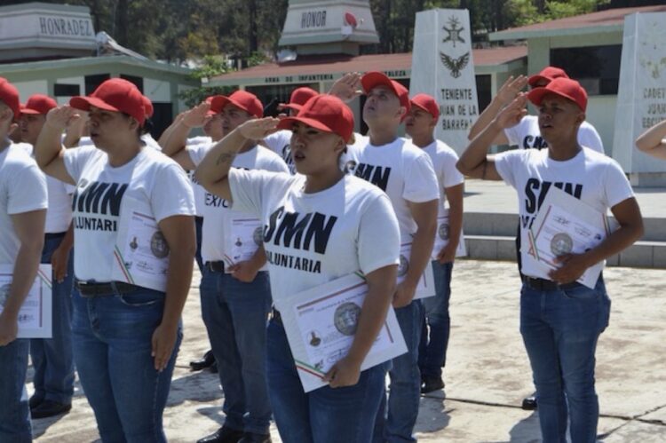 Jóvenes en uniforme y con gorra roja participan en ceremonia de graduación del Servicio Militar en Zamora.