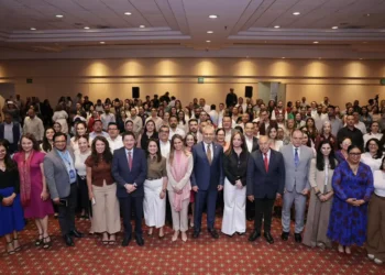 Grupo diverso de personas en evento formal en un salón de conferencias.