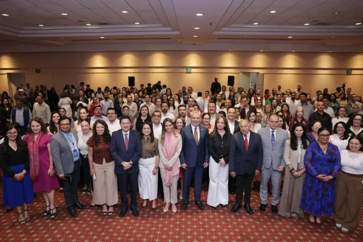 Grupo diverso de personas en evento formal en un salón de conferencias.