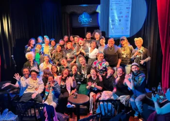 Grupo de personas en el escenario de El Breve, participando en un evento con risas y alegría.