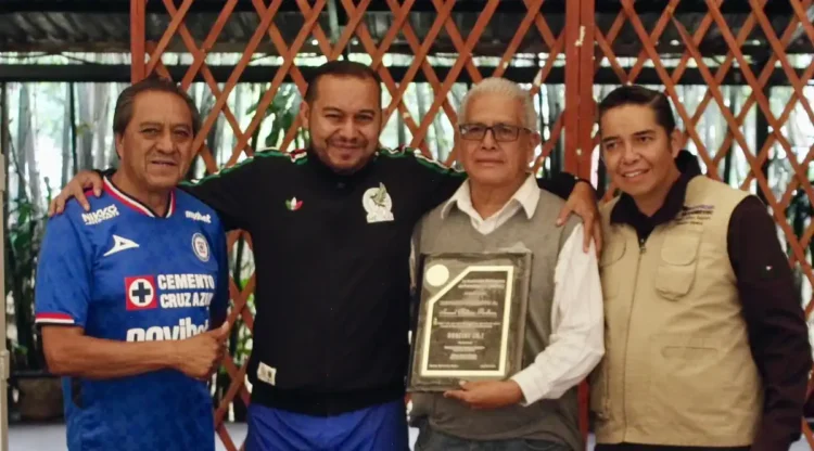 Cuatro personas posan con un reconocimiento en un evento formal en Michoacán, con fondo de madera y ambiente de celebración.