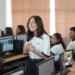 Joven estudiante en aula de computación en Michoacán, participando en clase con sus compañeros en un entorno escolar moder.